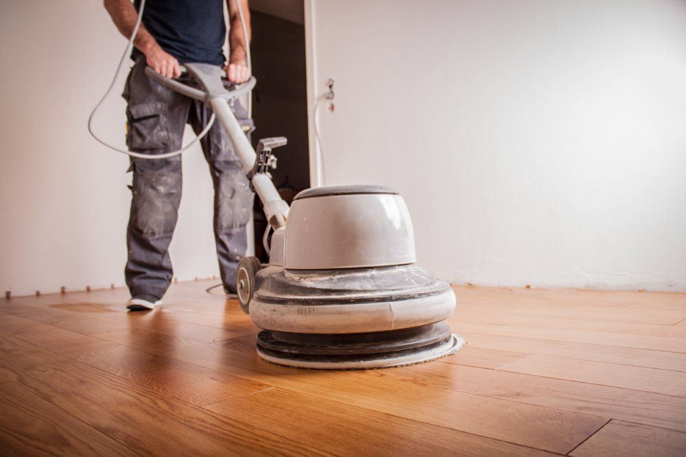 Handwerker ölt Parkettboden mit großer Poliermaschine.